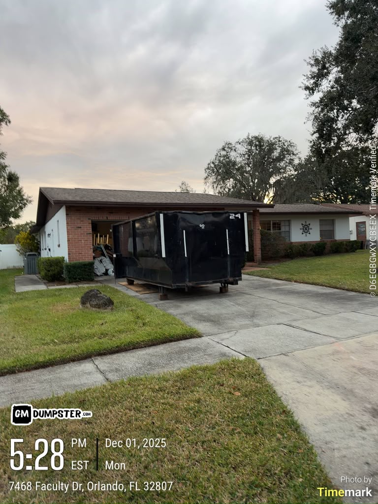 Black GM Dumpster roll-off container on a residential driveway in Orlando, Florida